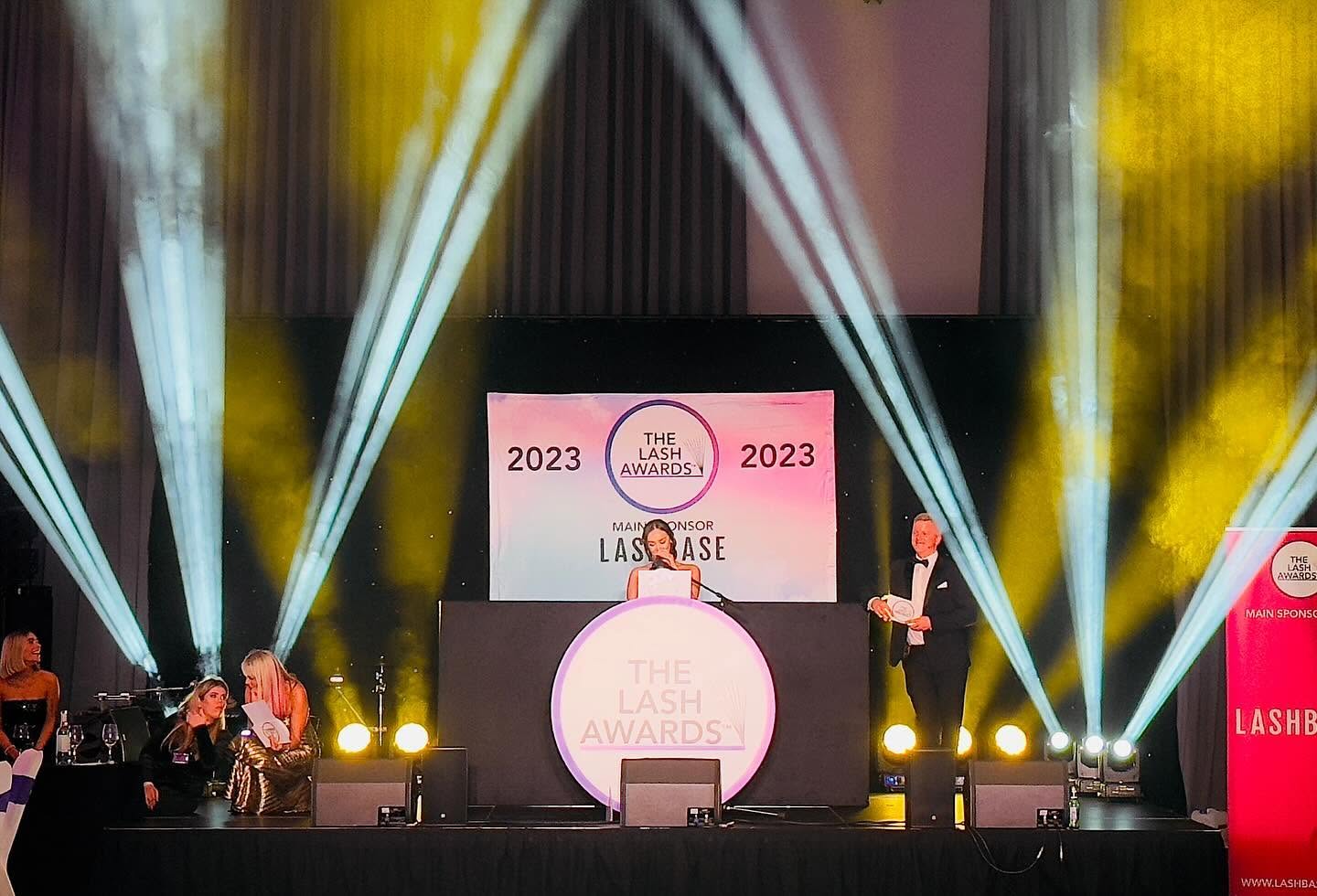 Awards stage with spotlight beams and presenters