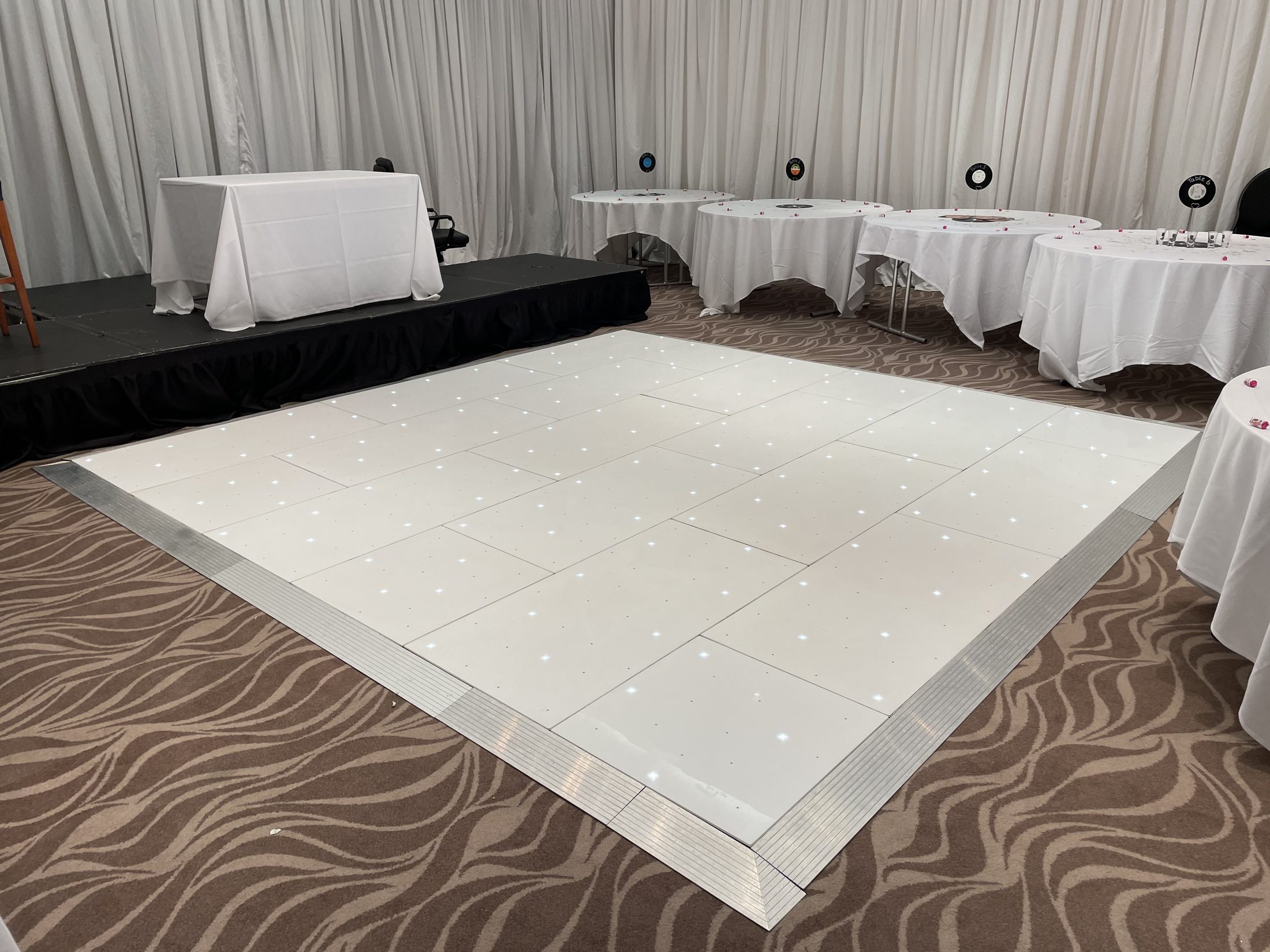 White starlight dance floor beside a low stage