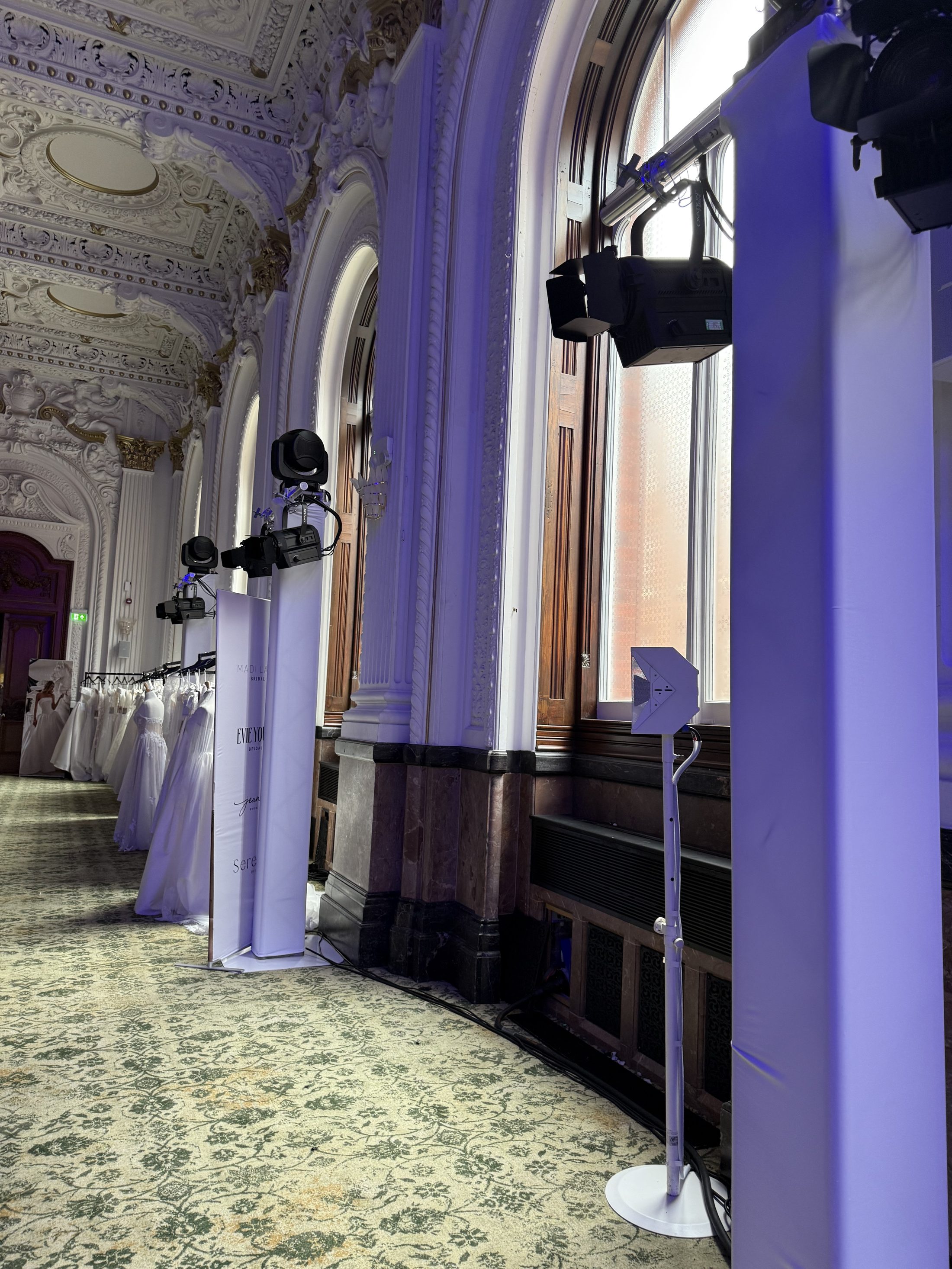 Line of white truss support towers and moving head lighting washing a fashion show catwalk