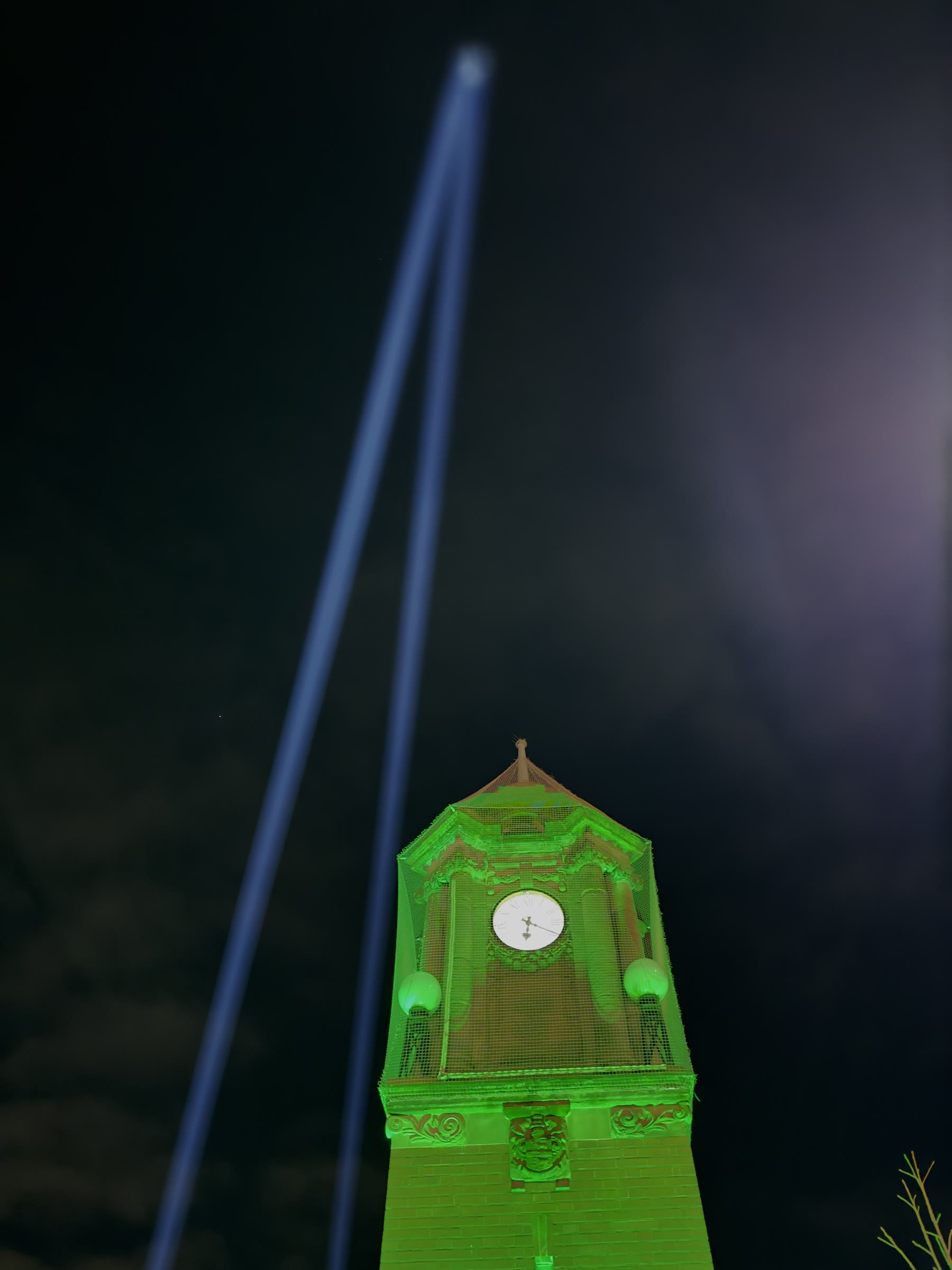 Wednesbury Clock Tower illuminated green with powerful sky beams for a charity event