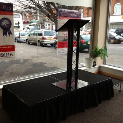 Black lectern on a small platform by a window