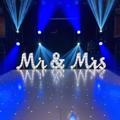 Mr and Mrs illuminated letters by a lit dance floor