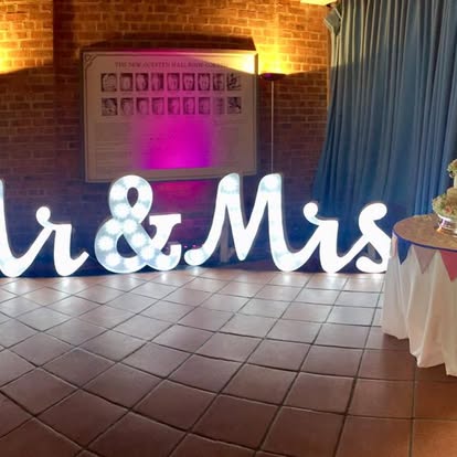 Mr and Mrs illuminated letters in a brick venue