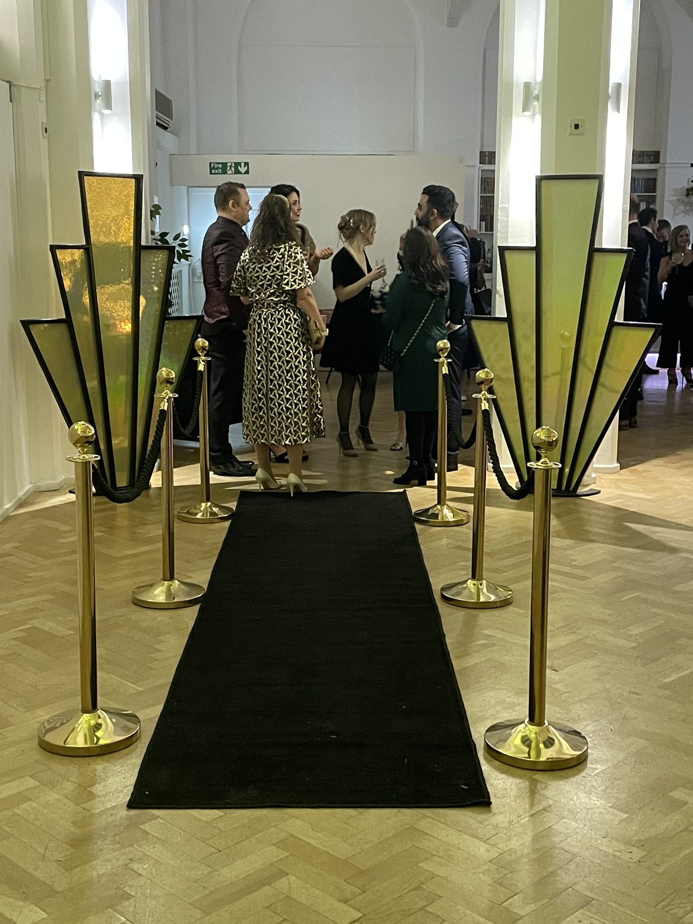 Art deco entrance props with black carpet and gold rope barriers
