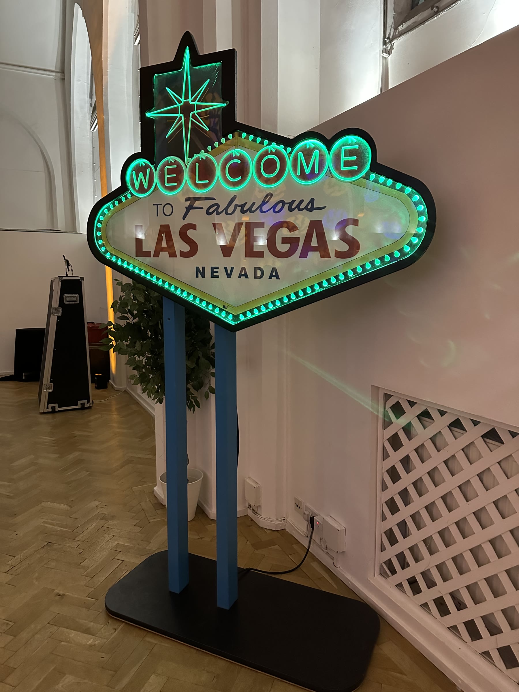 Full illuminated Las Vegas sign prop glowing green on its freestanding base