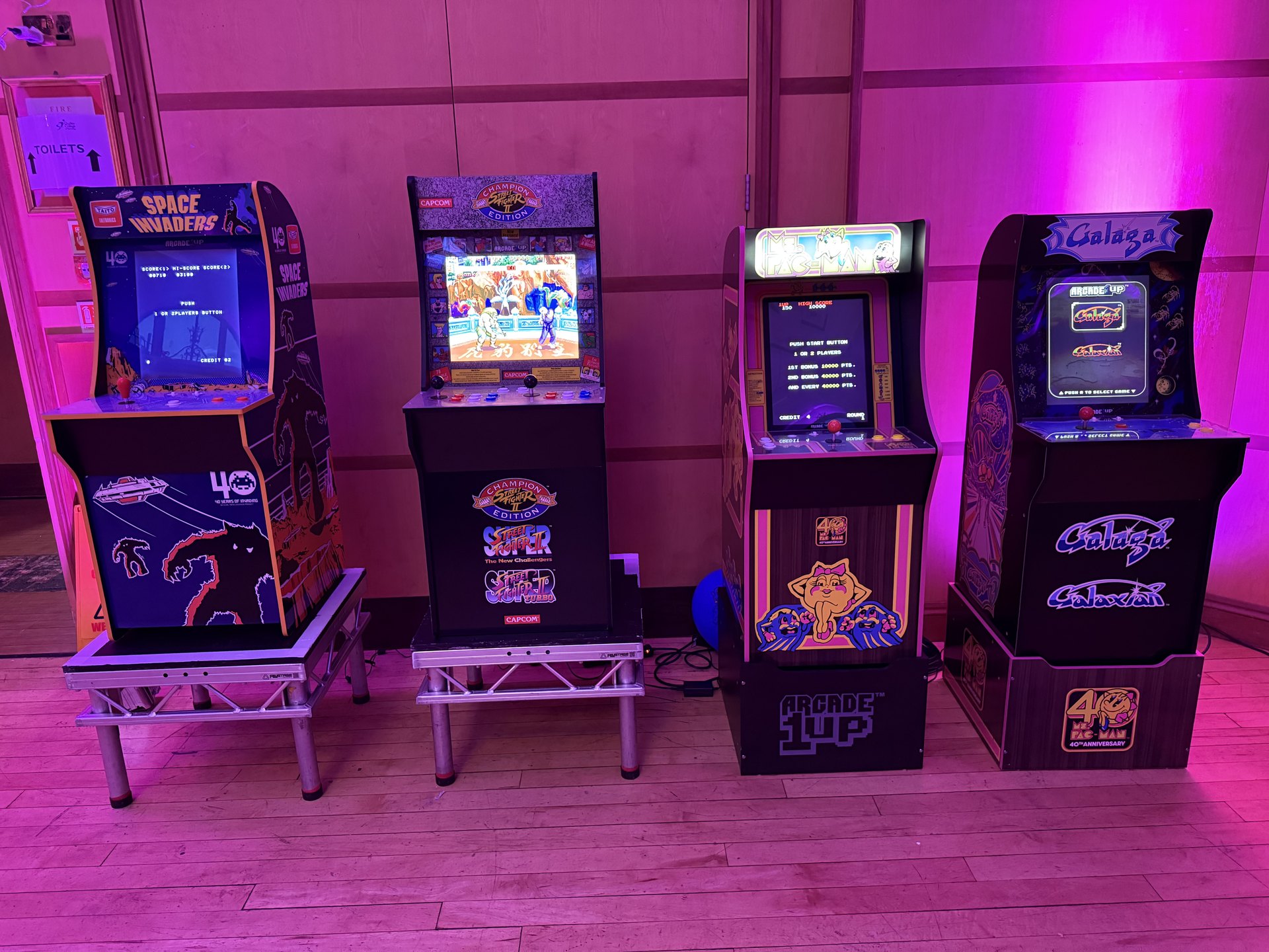 Front view of four illuminated retro arcade machines at an event