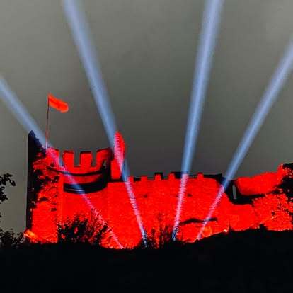 Sky beams above a red lit castle