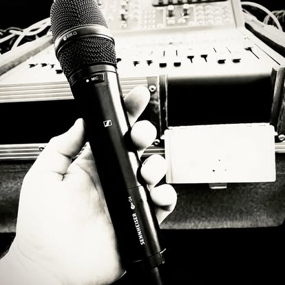 Handheld microphone in front of audio equipment