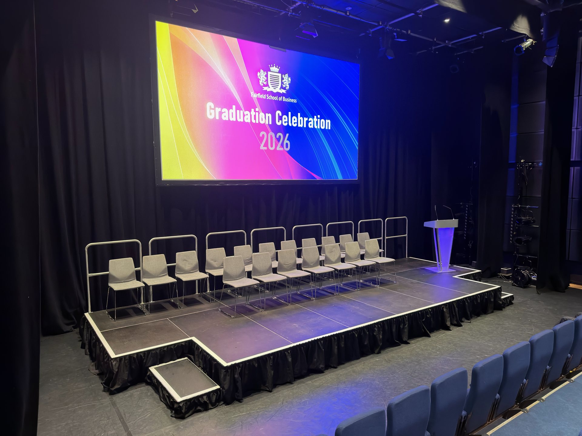 Stage platform with glass lectern and projected presentation screen