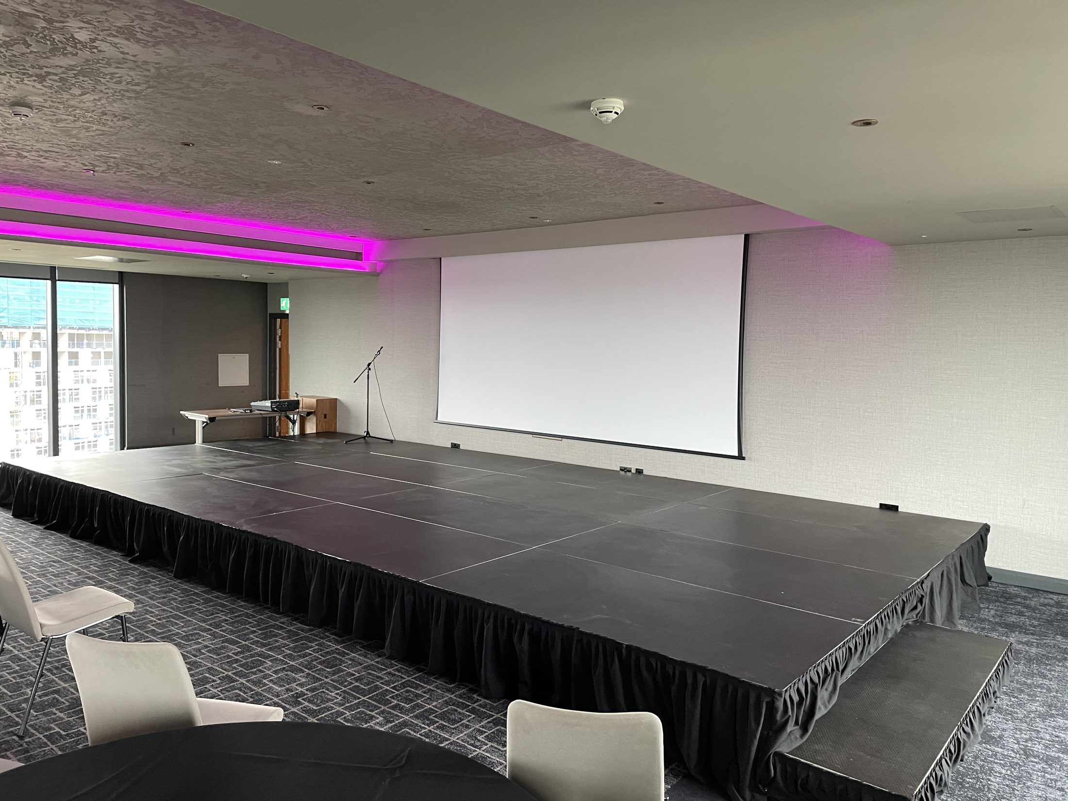 Large conference stage hire Birmingham setup with black skirt and projection screen