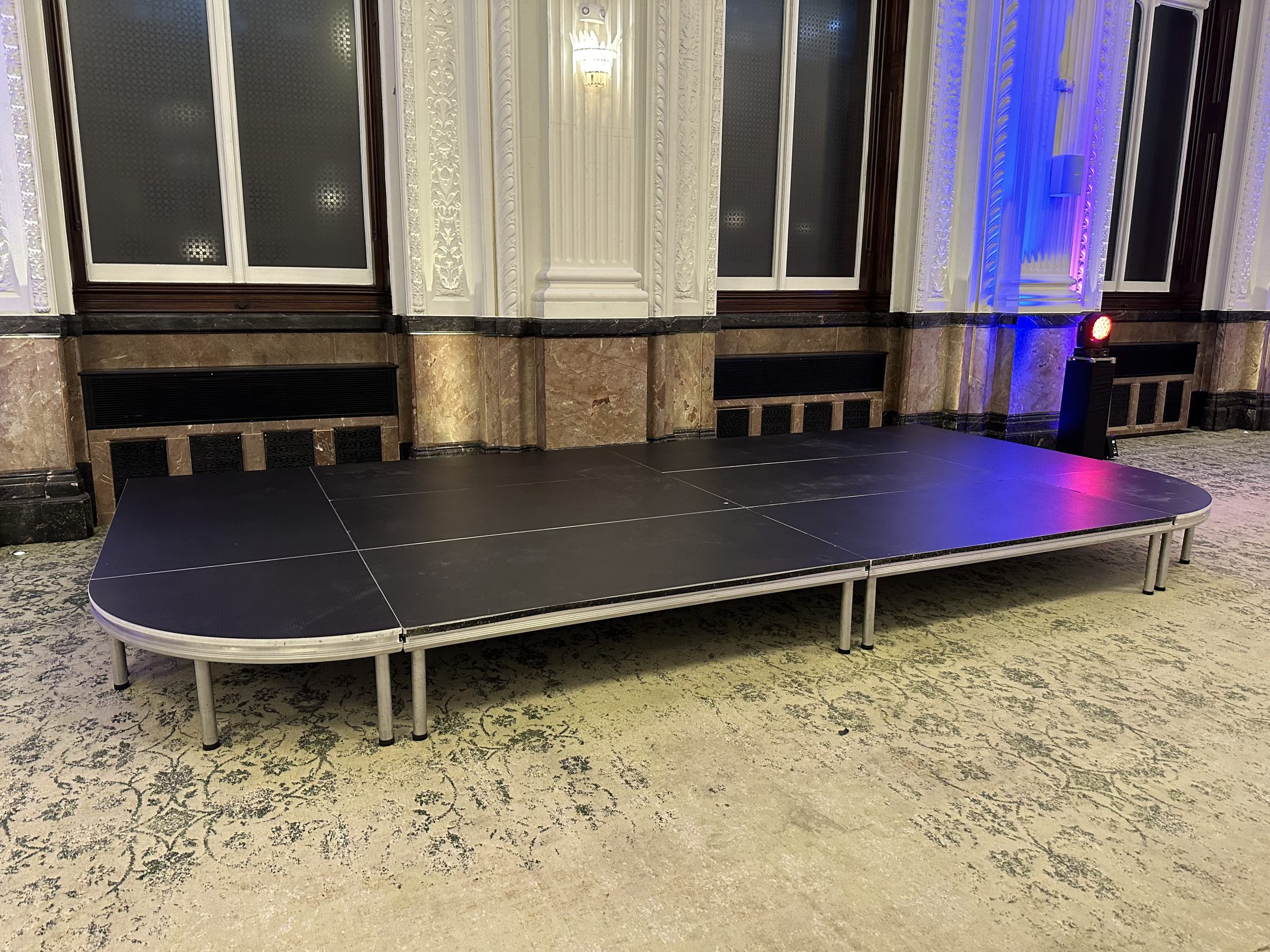 Low stage in a hotel function room with lighting nearby