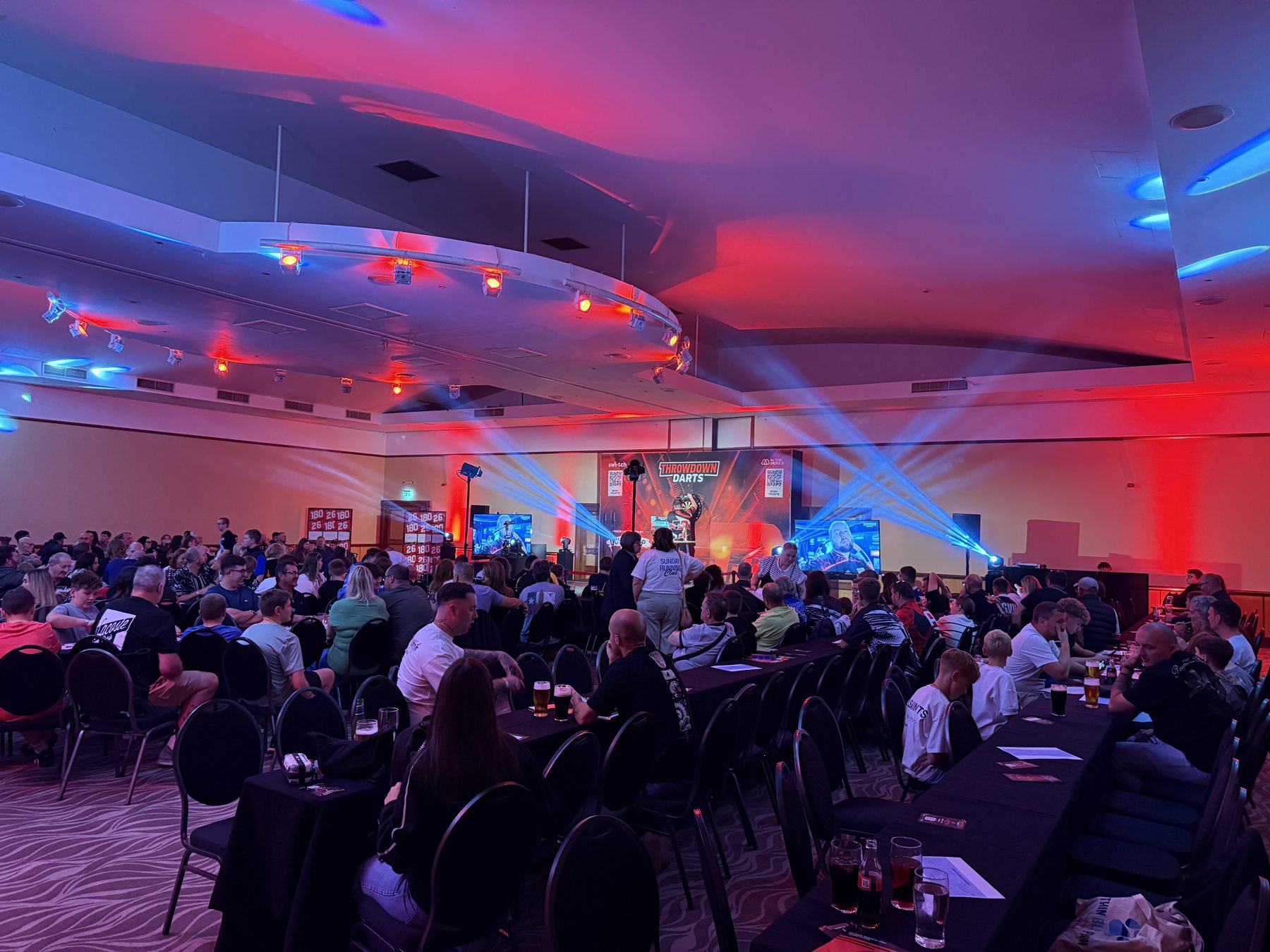 Full audience view of Throwdown Darts with red and blue event lighting at Copthorne Hotel Dudley