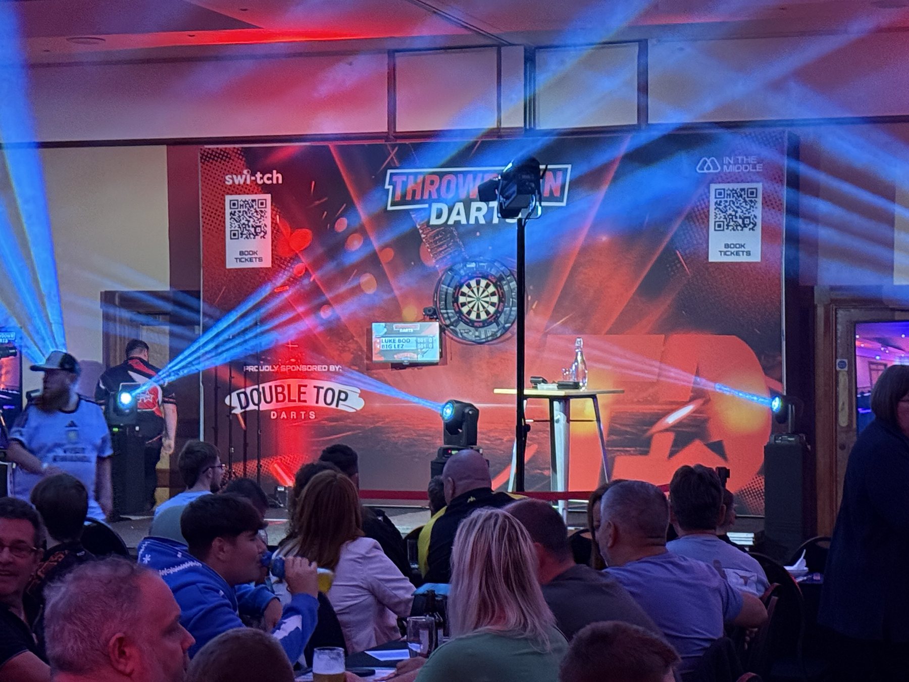 Blue moving-head beams crossing the Throwdown Darts stage