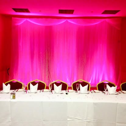 Pink wall wash behind top table draping