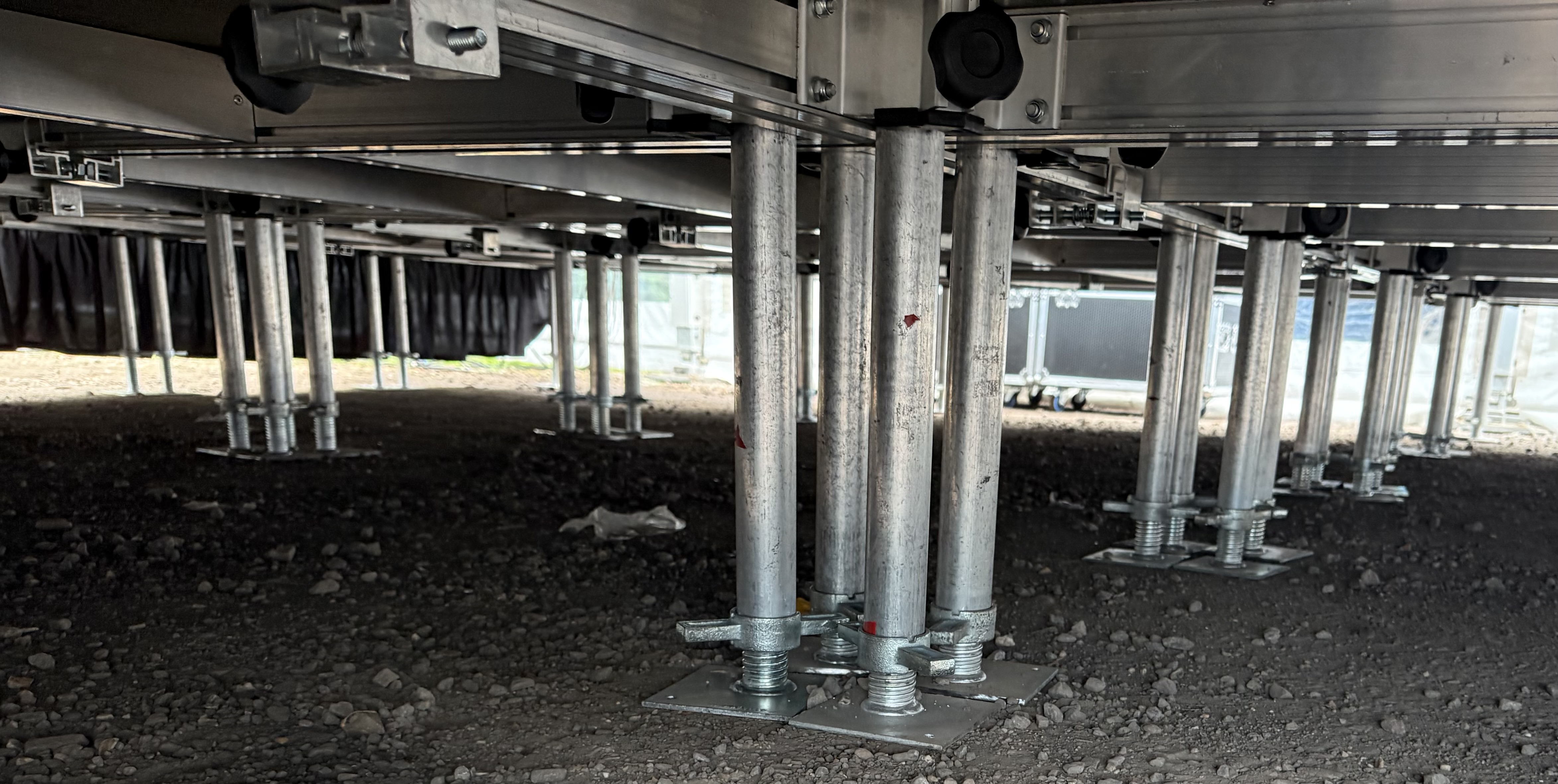 Adjustable stage support legs and deck framework underneath a temporary stage